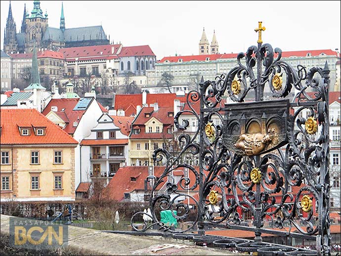 Um pedaço do Castelo de Praga e uma das esculturas que mostram São João Nepomuceno, na Ponte Carlos