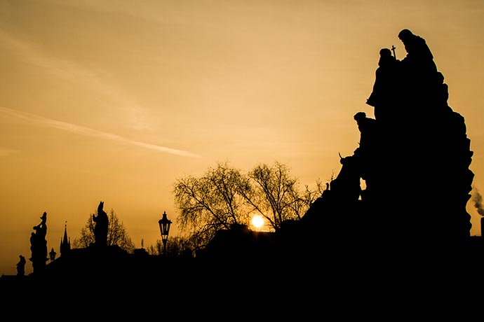 Ponte Carlos, suas estátuas e o sol nascendo no inverno, em Praga